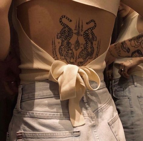 the back of a woman's body with tattoos on it