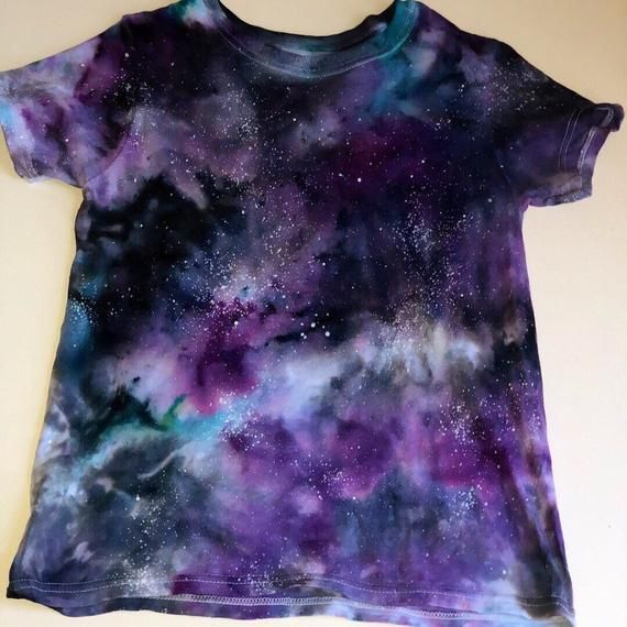 a t - shirt with purple and blue galaxy print on the front, sitting on a white surface