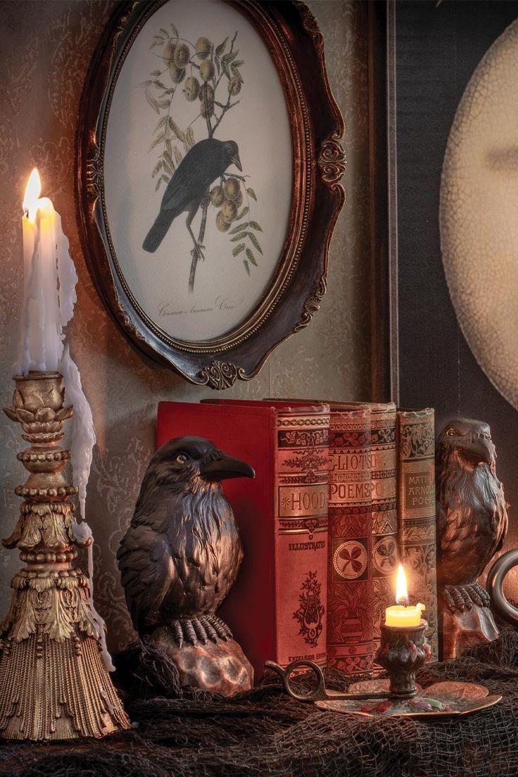 a black bird sitting on top of a table next to some books and candle holders