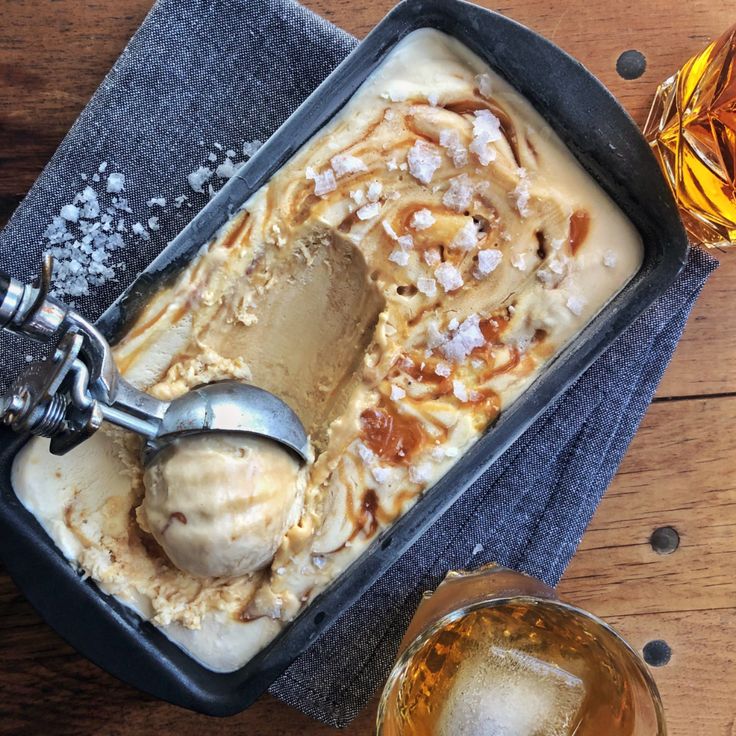 an ice cream sundae with caramel and nuts in a pan next to two glasses