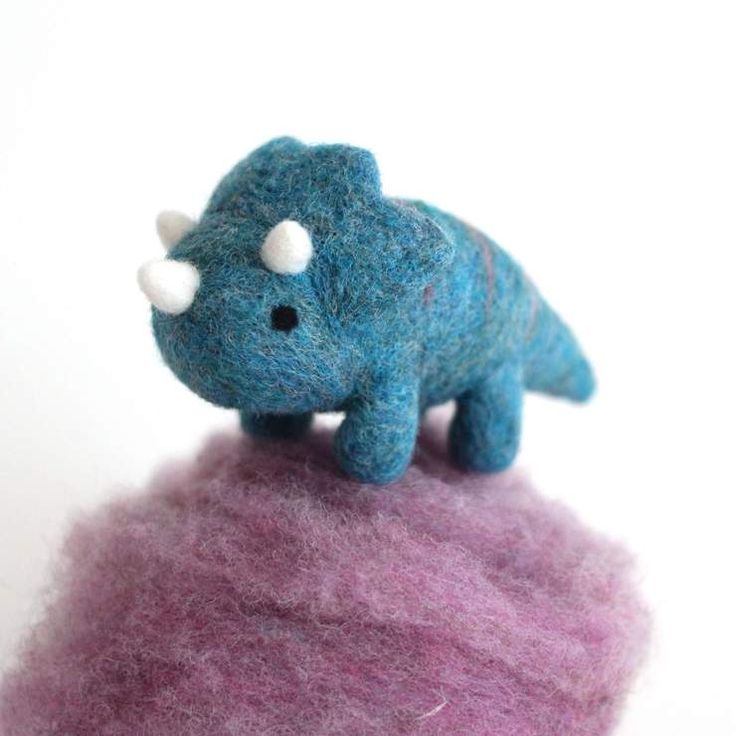 there is a small toy elephant on top of a pile of wool that has been dyed purple and blue