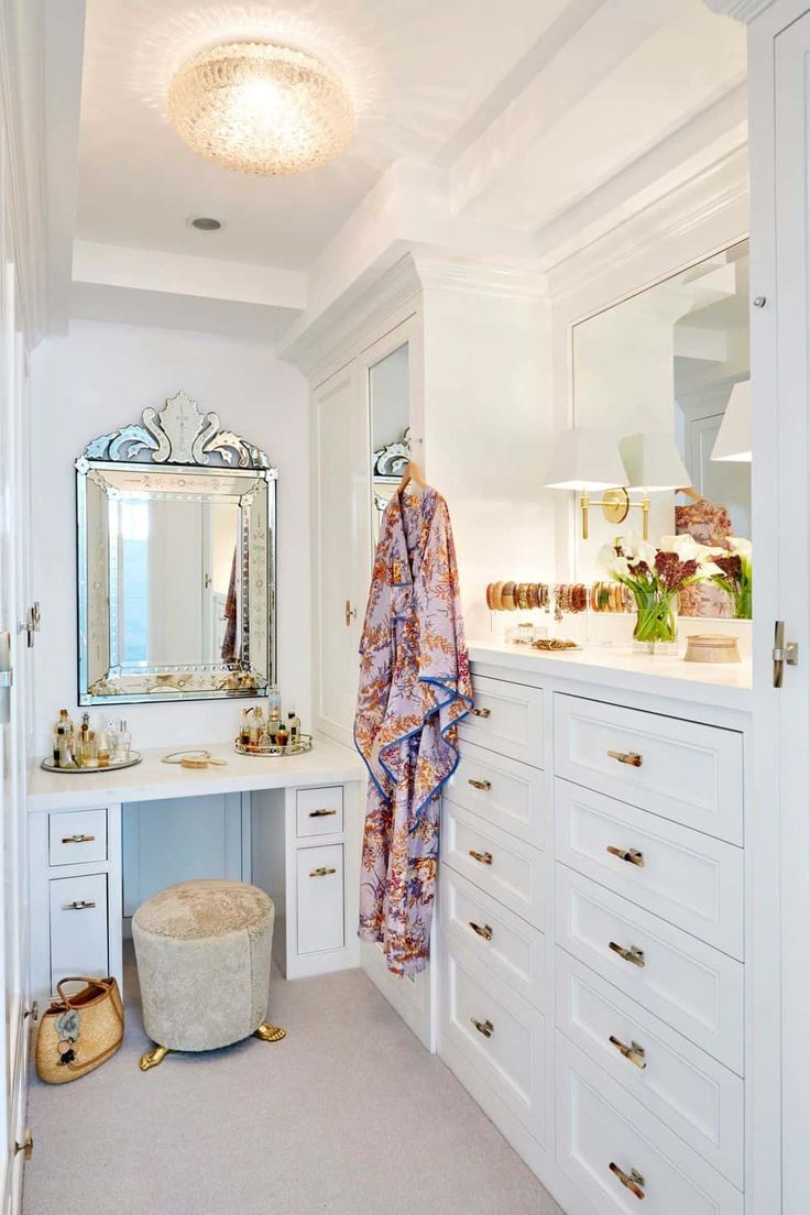 a dressing room with white cabinets and drawers