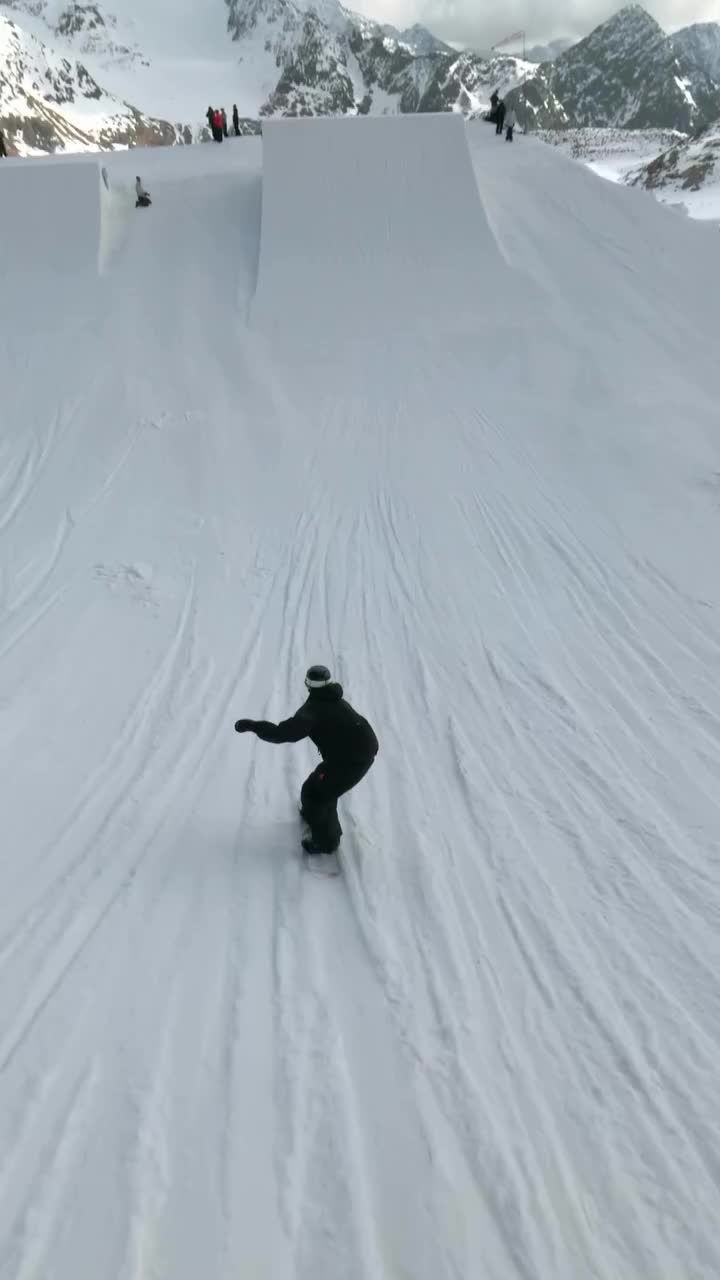 a man riding skis down the side of a snow covered slope in front of mountains