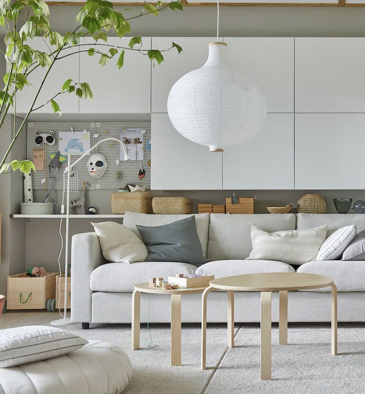 a living room filled with white furniture and lots of greenery on the wall behind it