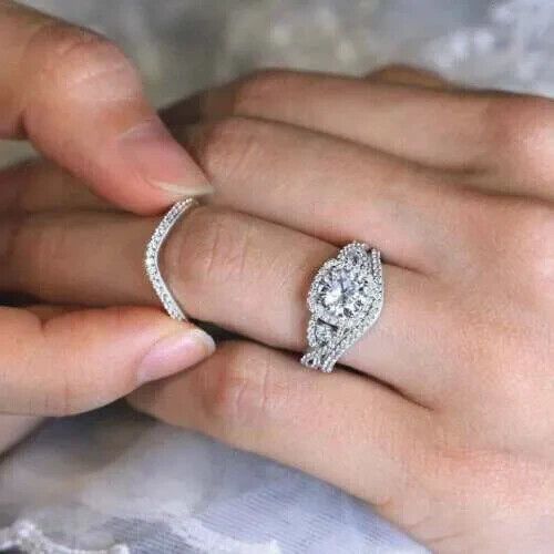 a woman's hand holding an engagement ring in her left hand, with the wedding band