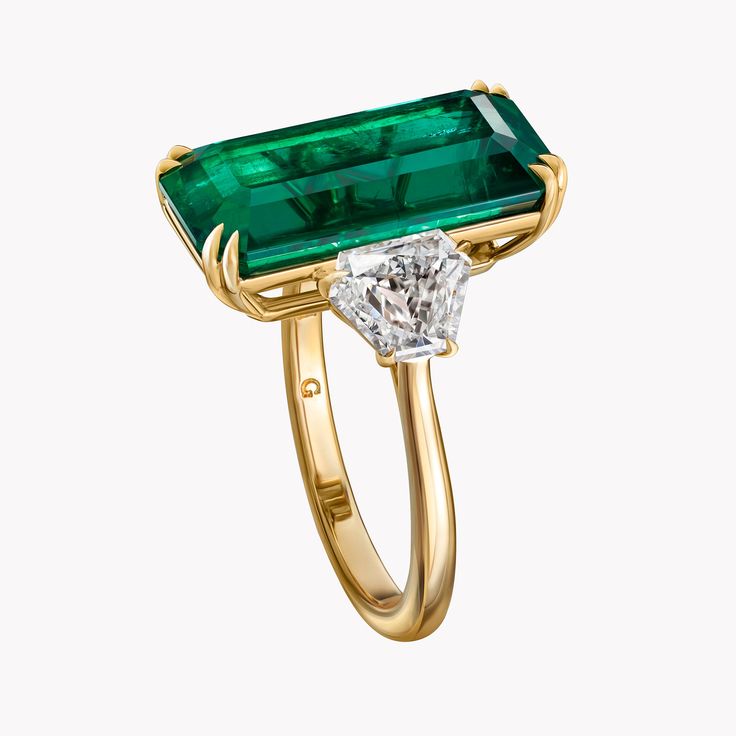 Bold and decadent, this ultra elongated emerald cut Zambian emerald is set between two brilliant cut shield diamonds in a delicate handmade four prong 18K yellow gold setting. Regal and refined emerald gemstones are an effortless pop of color to any ensemble. Evoke timeless radiance with this unforgettable statement piece that demands the spotlight. Elegant Emerald Collectible Ring, Classic Rectangular Emerald Gemstone Ring, Luxury Timeless Emerald-cut Emerald Ring, Zambian Emerald Ring, Luxury Faceted Emerald Rings, Luxury Square-cut Emerald Ring Fine Jewelry, Vintage Emerald Ring, Emerald Ring Vintage, Emerald Diamond Ring