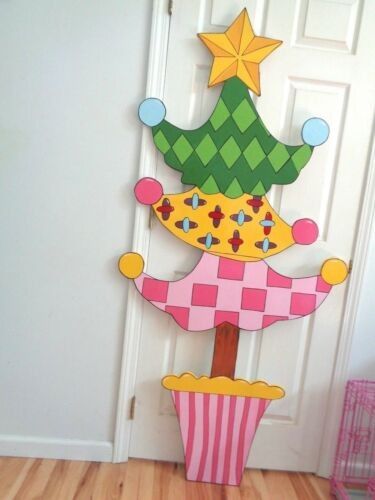 a cardboard christmas tree sitting on top of a wooden floor next to a white door