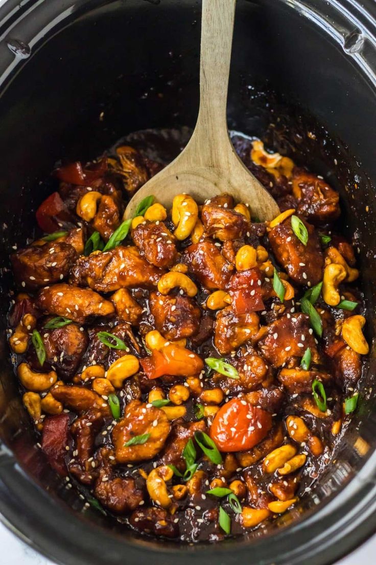 the slow cooker is full of chicken and beans, with a wooden spoon in it