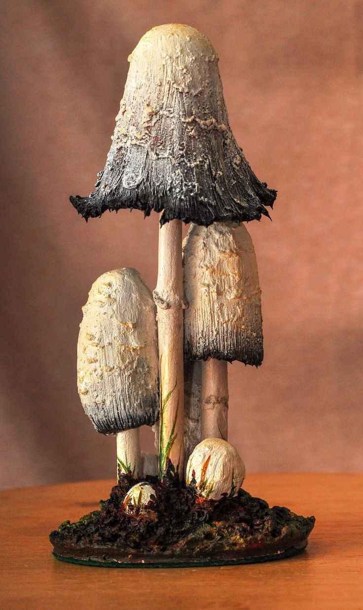 three mushrooms sitting on top of a wooden table next to each other with grass growing out of them