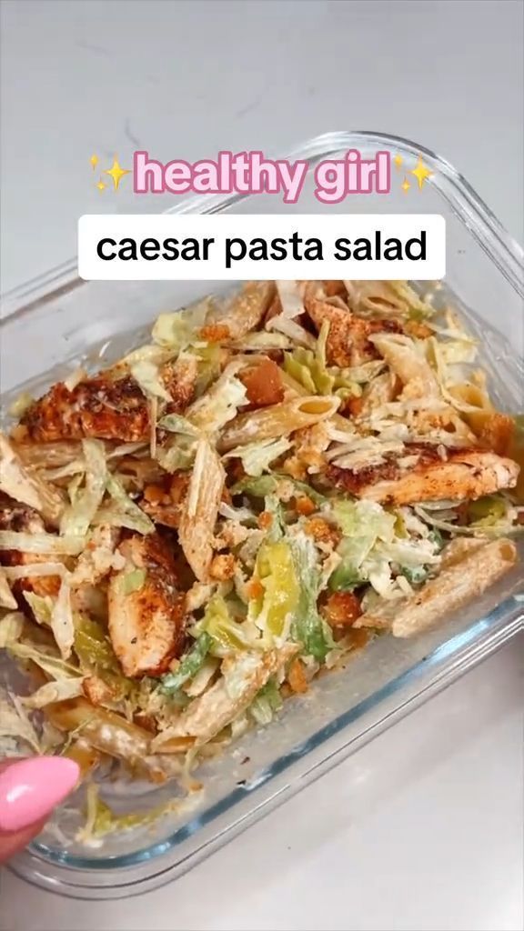 a plastic container filled with food on top of a white table next to a pink hand