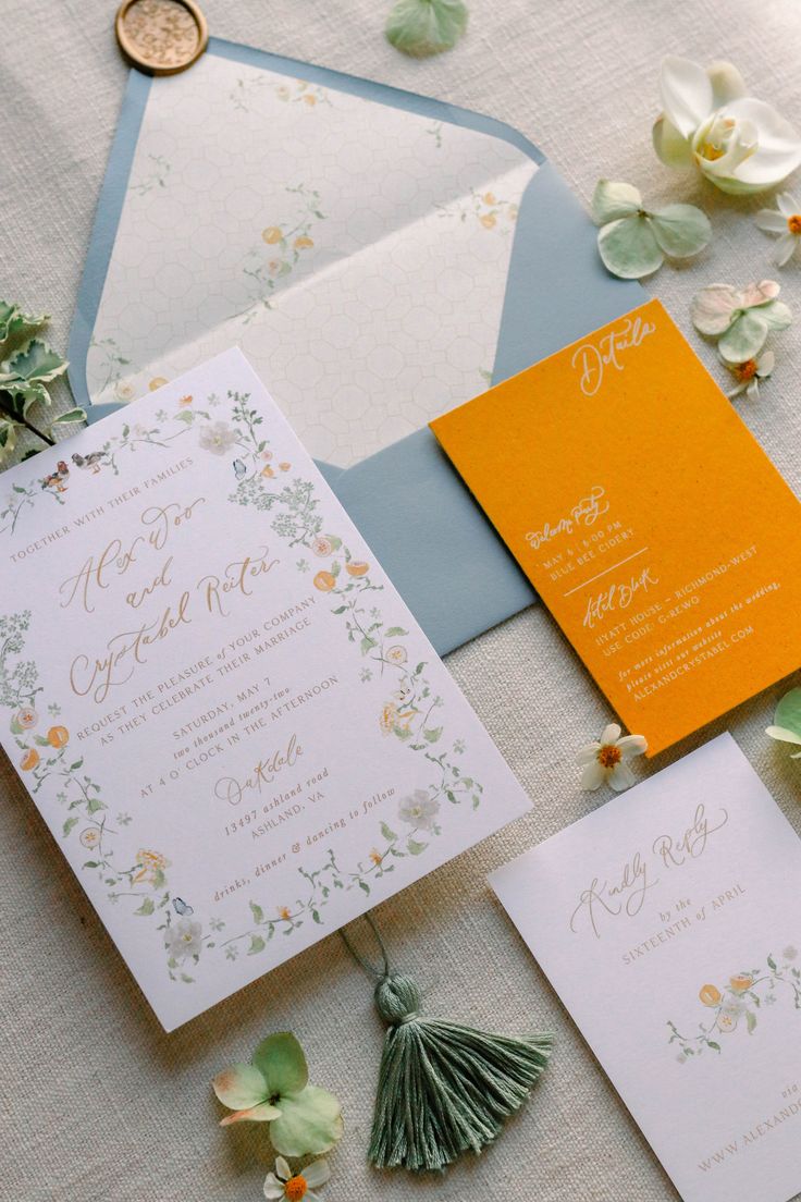 the wedding stationery is laid out on top of the table with flowers and greenery