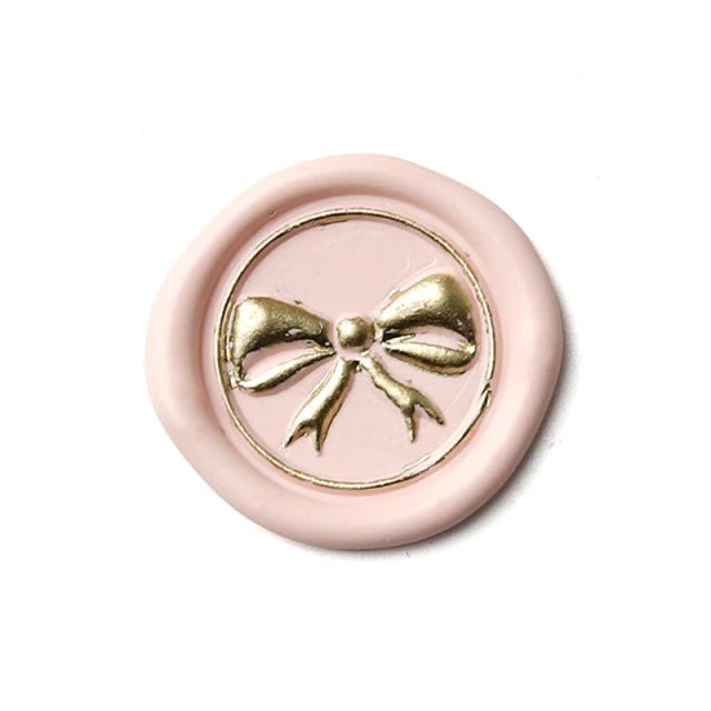 a pink and gold button with a bow on it