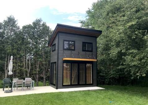 a small black house sitting on top of a lush green field