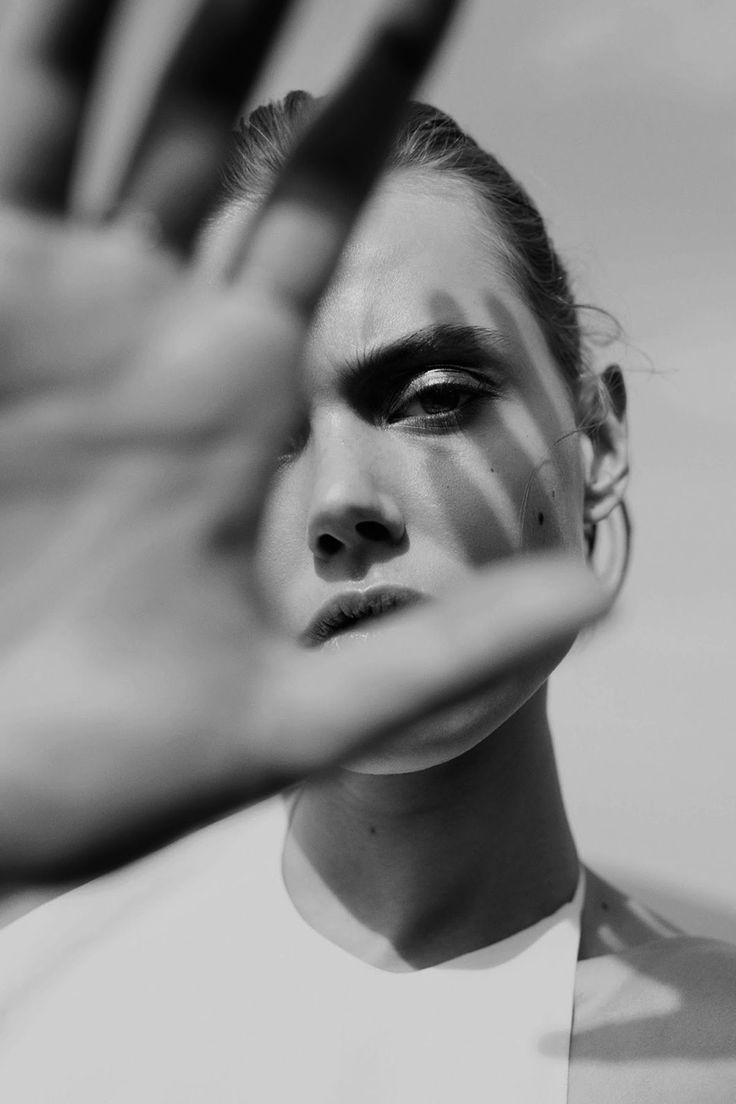 a black and white photo of a woman's face with her hands in the air