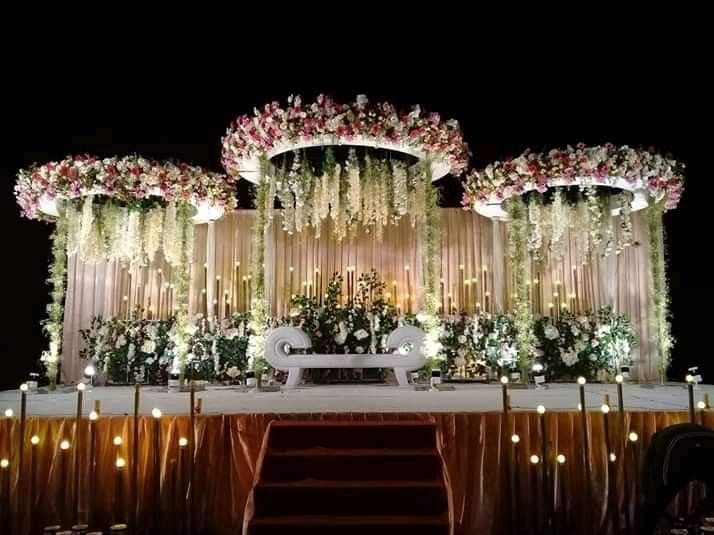 an outdoor stage decorated with flowers and greenery for a wedding or special event in the evening