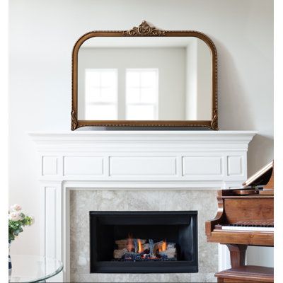 a living room with a piano and a mirror on the wall over the fire place