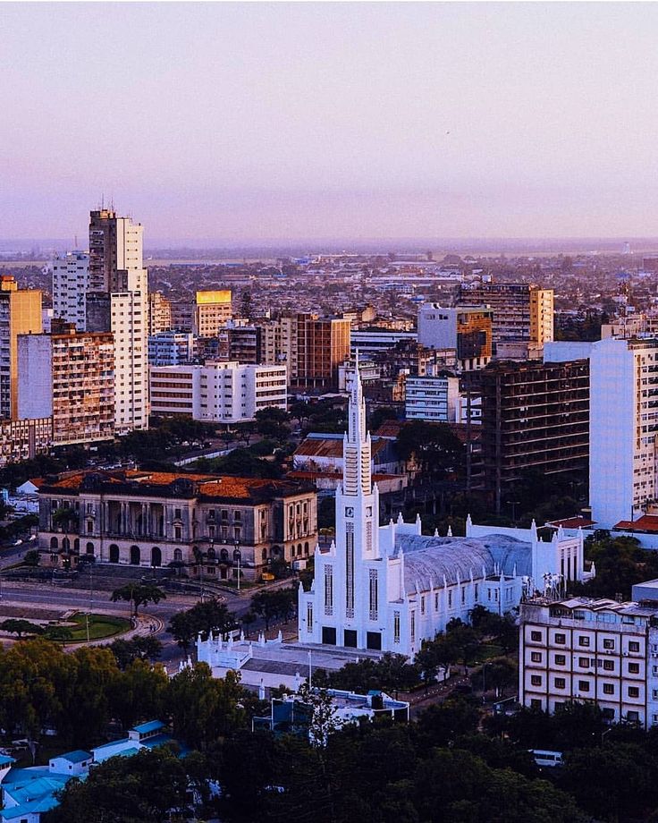 an aerial view of a city with tall buildings in the foreground and trees on the other side