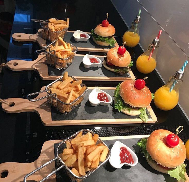 several trays filled with different types of food on wooden serving boards next to drinks