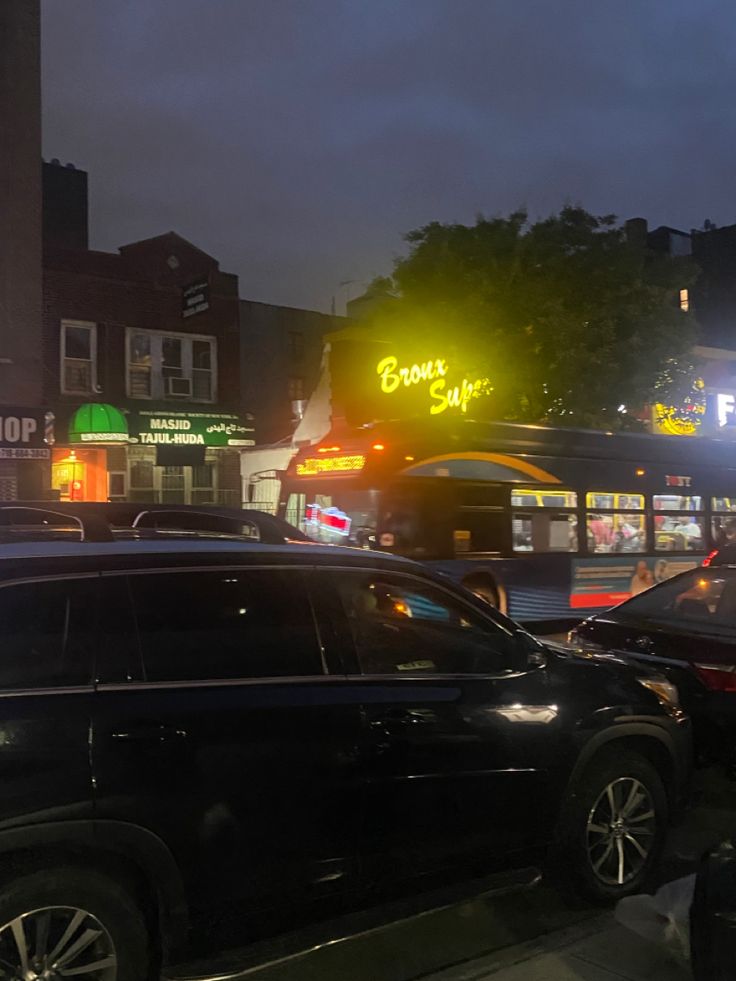 cars are parked on the side of the road at night in front of a bus stop