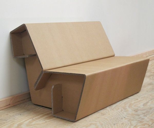 a cardboard couch sitting on top of a wooden floor next to a white wall and wood floor