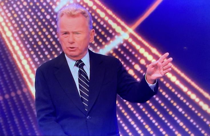 a man in a suit and tie standing on stage with his hands out to the side