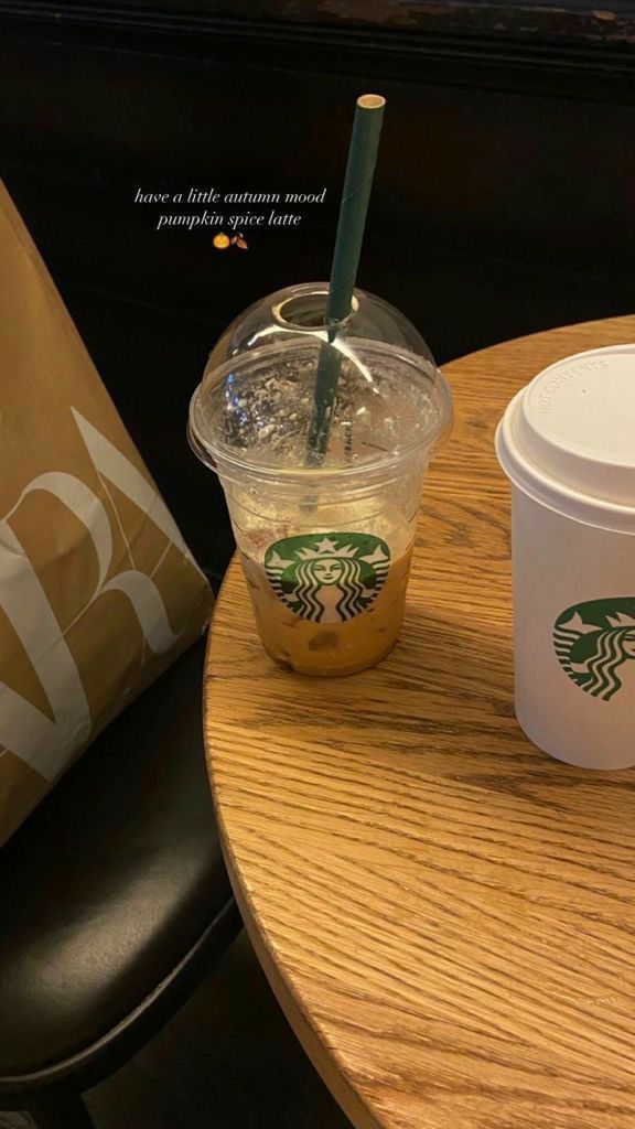 two starbucks cups sitting on top of a wooden table