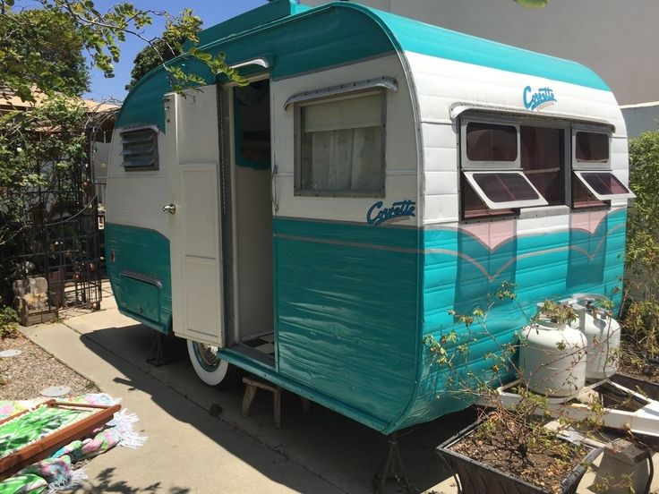 an old blue and white trailer parked in front of a house