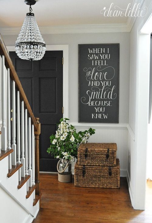 a foyer with a chandelier, basket and flowers on the floor in front of it