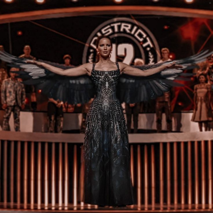 a woman in a black dress with wings on stage