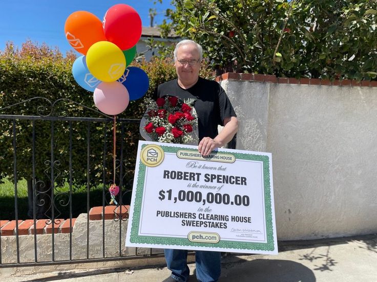 a man holding up a large check for $ 1, 000 in front of a fence