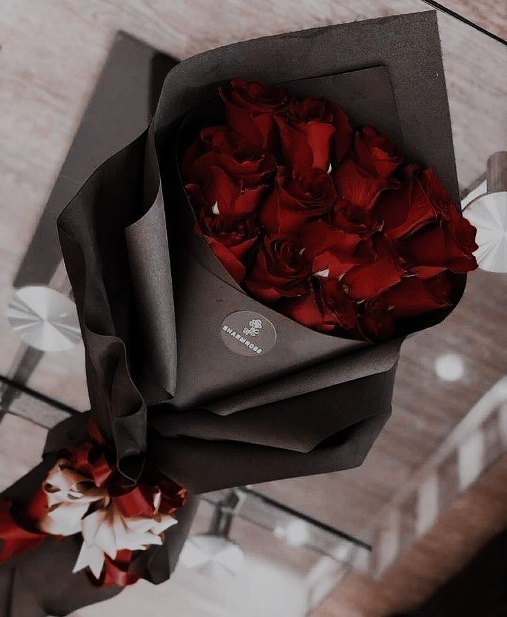 a bouquet of red roses in a black paper bag