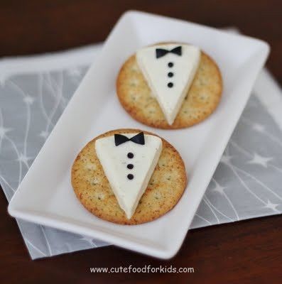 two cookies decorated to look like the bride and groom's suits are on a plate