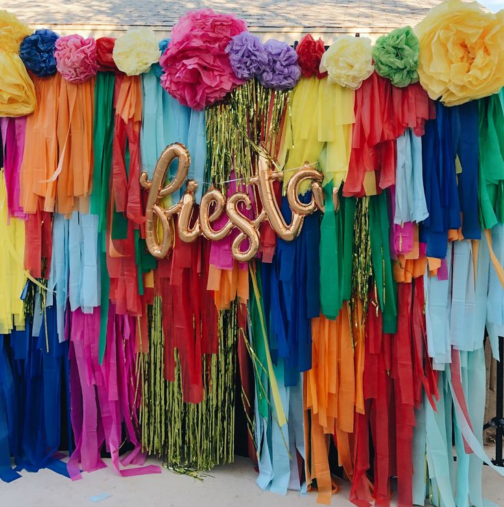 colorful streamers and balloons with the word fiesta spelled out in gold letters are hanging on a wall