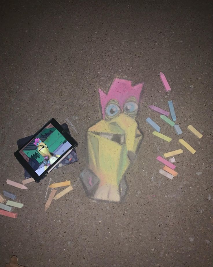 a chalk drawing of a dog with colored crayons on the ground next to it