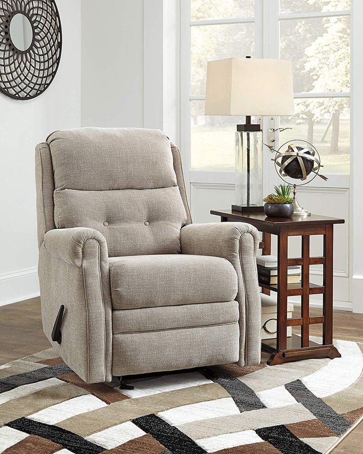 a living room with a large rug and a reclining chair in the middle of it