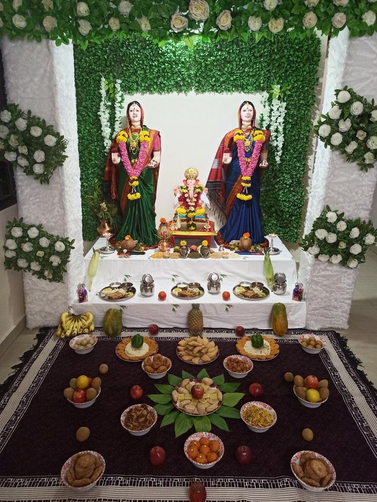 there are two statues in the middle of a table with food on it and flowers all around