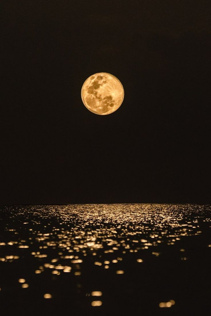 the full moon shines brightly in the dark night sky over the ocean with reflections on the water