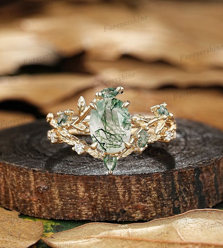 a close up of a ring on top of a piece of wood with leaves around it