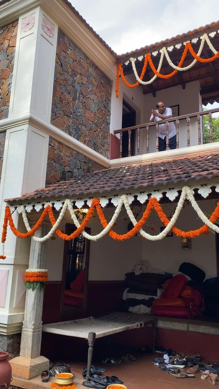 a man standing on the balcony of a house decorated with orange and white garlands