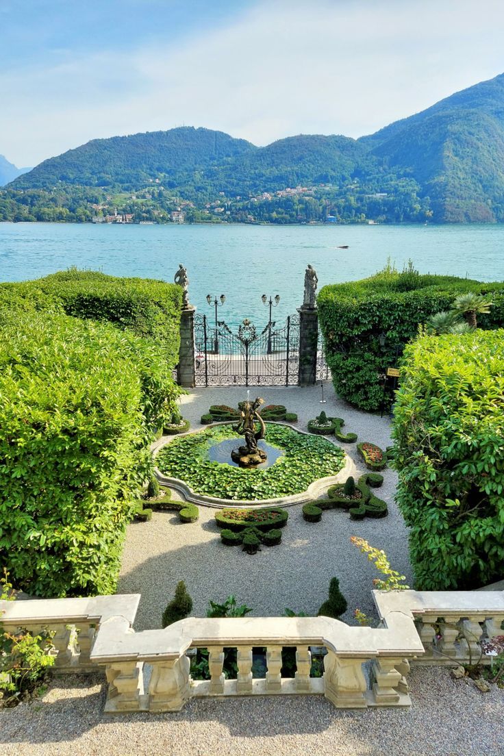 an outdoor garden with water and mountains in the background