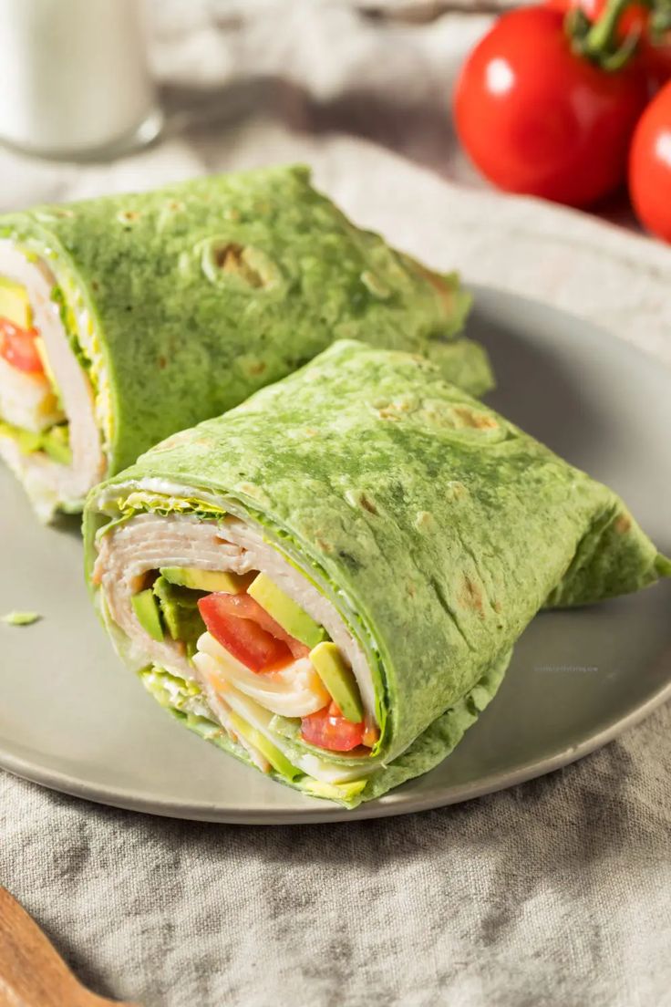 two wraps on a plate with tomatoes in the background