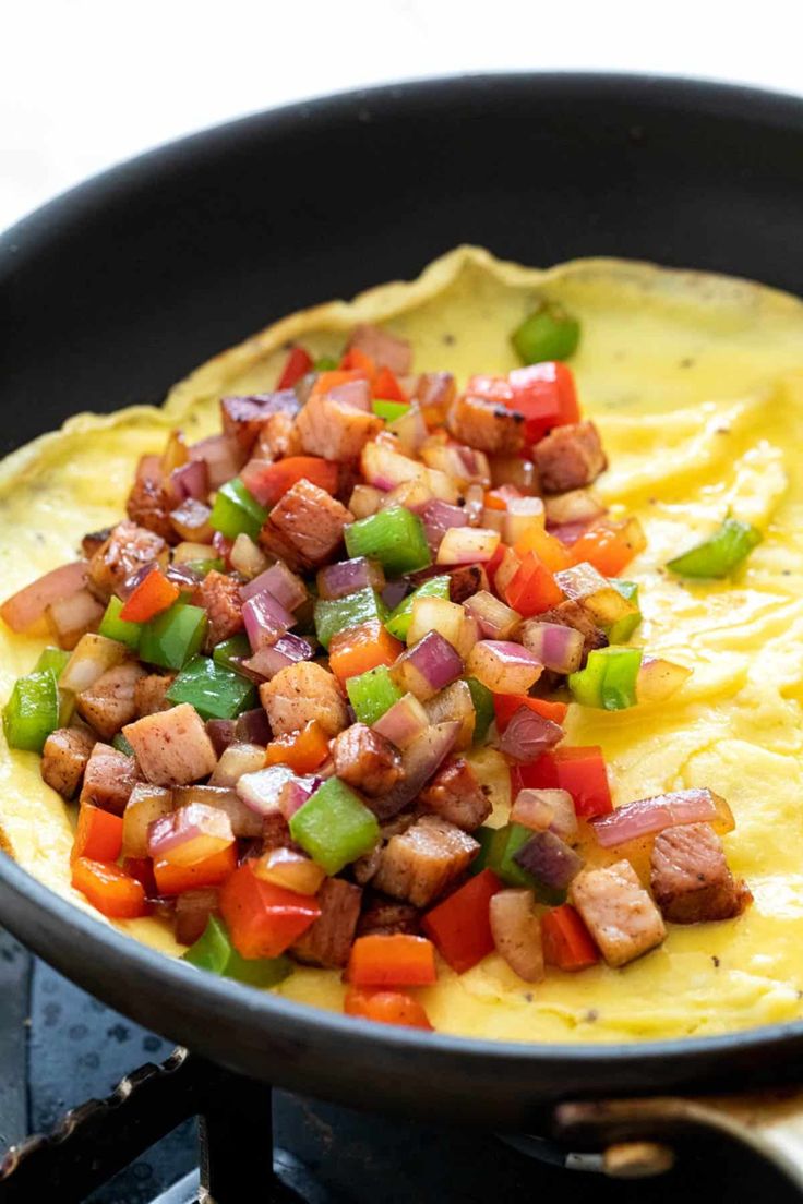 an omelet with meat and vegetables in a skillet