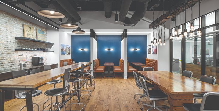 an empty restaurant with wooden tables and stools in the center, along with blue walls