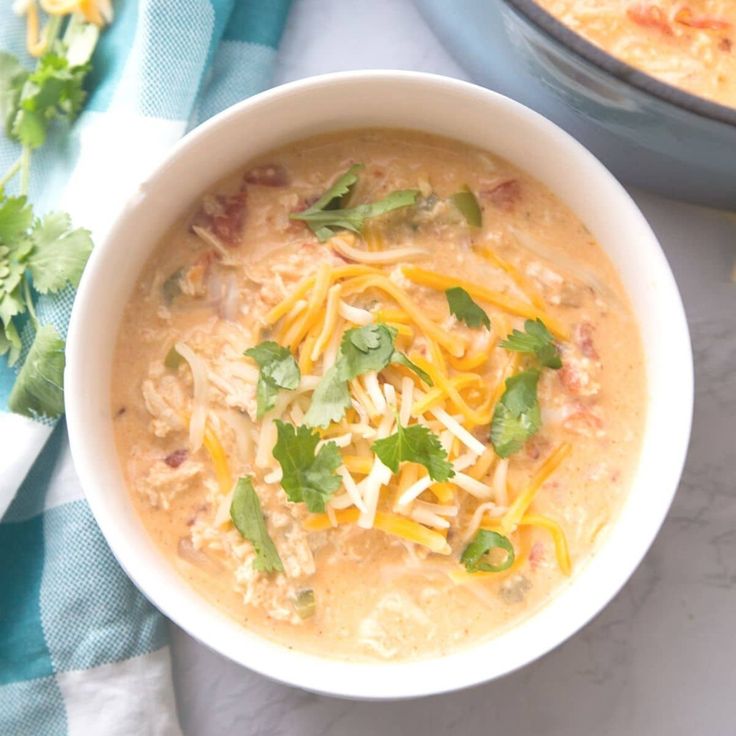 a bowl of soup with cheese and cilantro garnish on the side