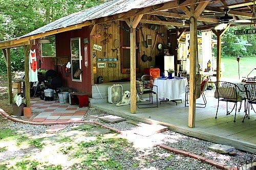 a covered patio with tables and chairs in the woods next to a picnic table set up