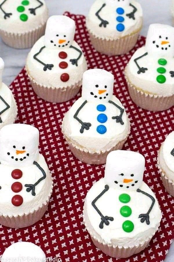 cupcakes decorated like snowmen on a red and white tablecloth