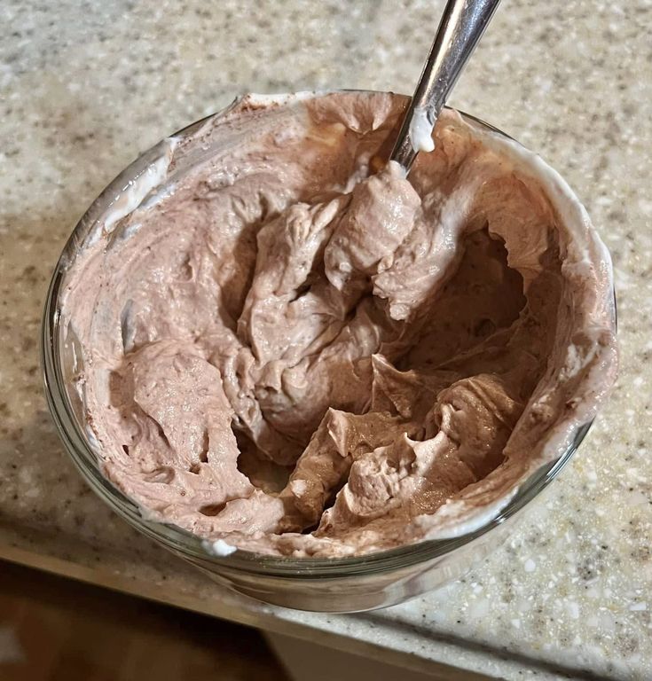 a glass bowl filled with chocolate frosting on top of a counter