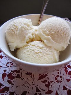 two scoops of ice cream in a white bowl on a lace doily with a spoon