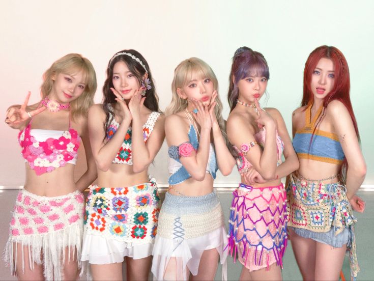 four beautiful young women standing next to each other in front of a white wall and wearing colorful clothing