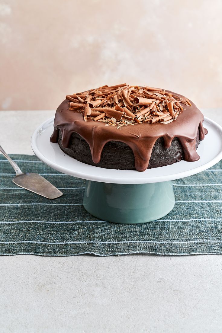 a cake with chocolate frosting and nuts on top sitting on a plate next to a fork